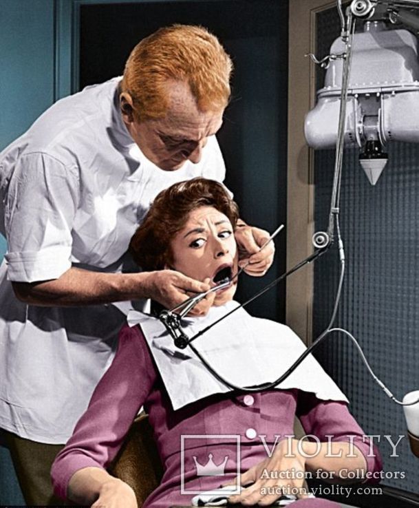 Рыжий стоматолог санирует зубы испуганной даме.