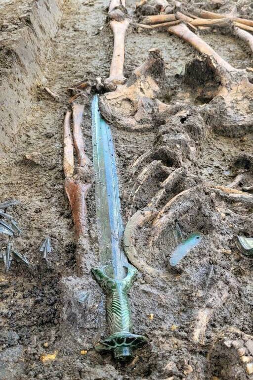 Photo: Excavation of a Bronze Age burial. A sword near the bones, and arrowheads can also be seen.