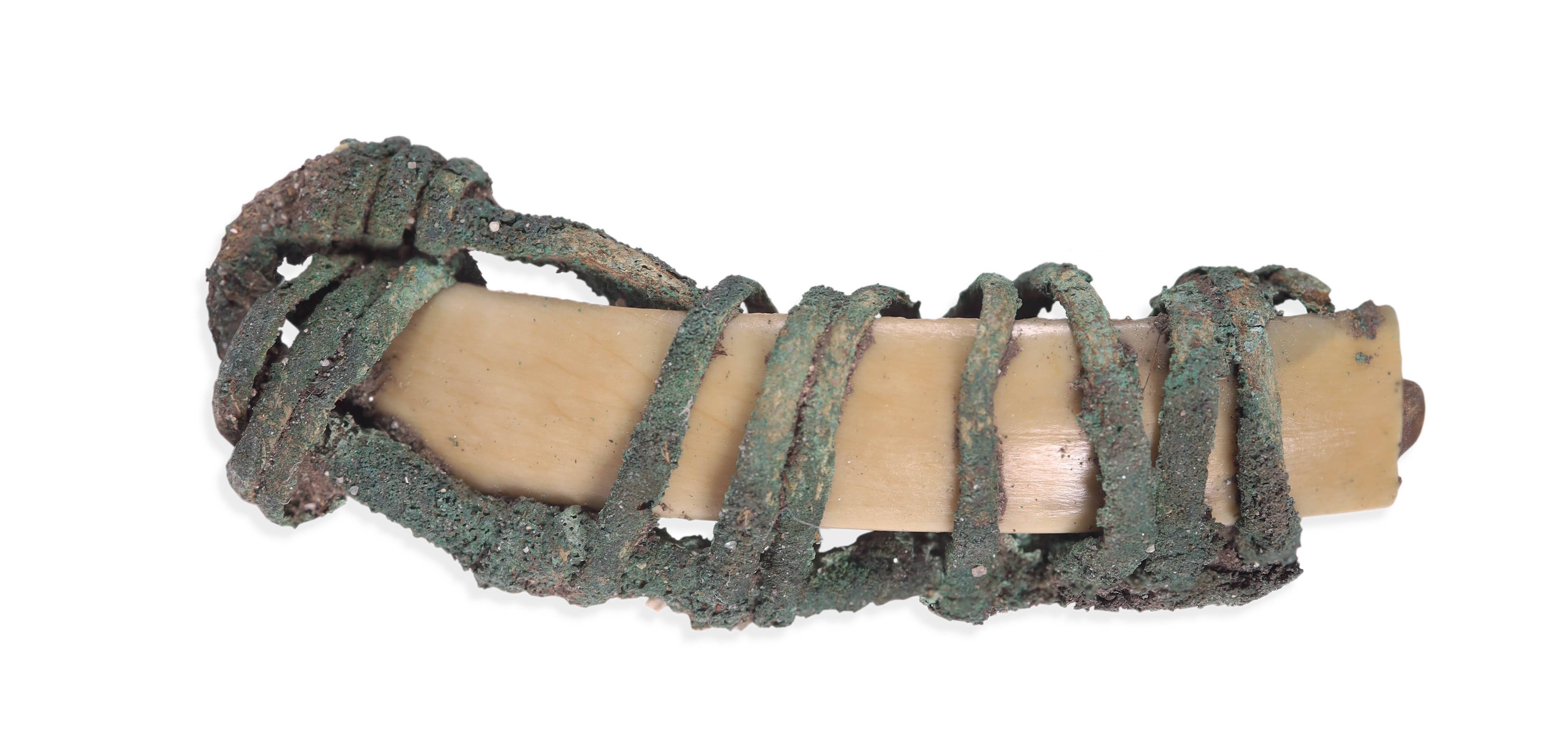 Ця підвіска (знайдена на дні ями) складається з зуба тварини, загорнутого в металеві прикраси.