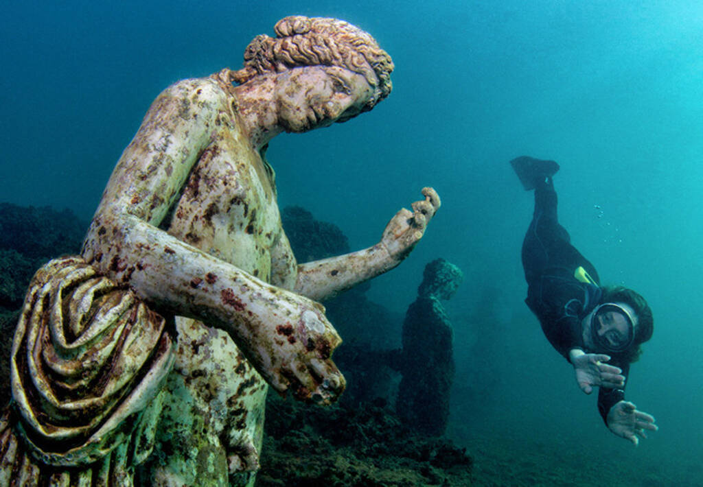 A diver swims near a replica statue of Dionysus, the god of wine, in a nymphaeum in Baiae.